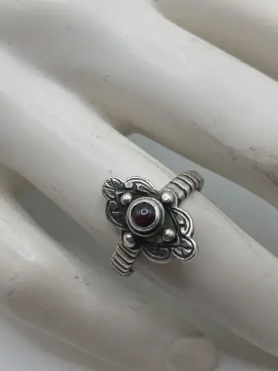 Zilverkleurige ring met rood steentje en bloemmotief – kavel bij De Kringwinkel, Diest