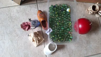 Grote partij glazen knikkers in een plastic bak samen met diverse kleine decoratie-artikelen – kavel bij Goeiendeal, Houthalen-Helchteren