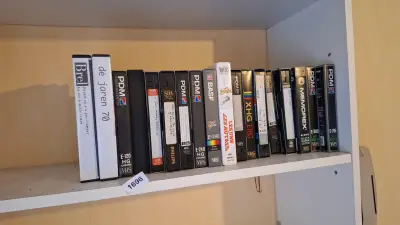 Rij van 18 vhs-videocassettes waaronder titels van Jacques Brel en de jaren 70 – kavel bij Goeiendeal, Houthalen-Helchteren
