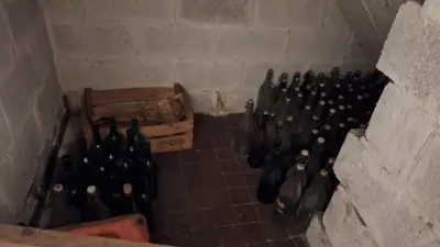 Grote partij lege glazen flessen verdeeld over de vloer en een houten krat – kavel bij Goeiendeal, Houthalen-Helchteren