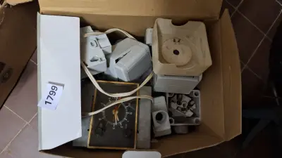 Kartonnen doos gevuld met elektrotechnische componenten waaronder schakelaars en een analoge tijdschakelklok – kavel bij Goeiendeal, Houthalen-Helchteren