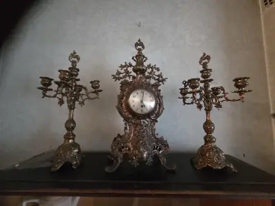 Driedelig schouwgarnituur bestaande uit een rijkelijk gedecoreerde tafelklok met Romeinse cijfers en twee bijbehorende 5-armige kandelaren lot 57 – kavel bij Goeiendeal, Jette