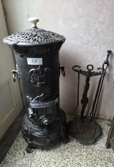 Klassieke ronde kolomkachel gietijzer(model nr. 109 "Ciney" Regence) met opengewerkte details en reliëfdecoratie, inclusief bijbehorend haardstel m… – kavel bij Goeiendeal, Jette