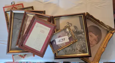 Stapel diverse fotolijsten met zwart-wit portretten, trouwfoto's en een ingelijste Franstalige tekst – Lot 139 – kavel bij Goeiendeal, Jette