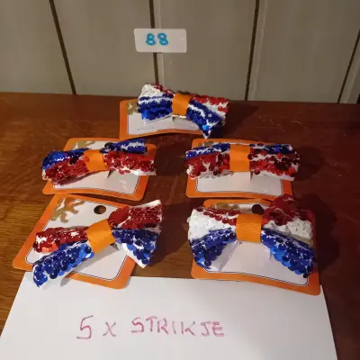 5 stuks strikjes met lovertjes / pailletten in de kleuren rood, wit en blauw, met een oranje lint (Lot: 88) – kavel bij Goeiendeal, Lommel