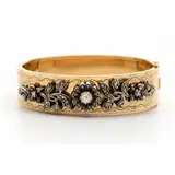 Geelgouden stijve armband, buitenzijde gegraveerd met krullen, bovenzijde bezet met zilveren florale motieven, waarin roosgeslepen diamanten, met b… – kavel bij Venduhuis De Eland