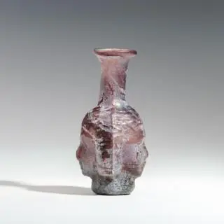A rare Roman aubergine coloured glass janus-head shaped bottle, 1st - 2nd century CE – kavel bij Veilinggebouw De Zwaan, Amsterdam