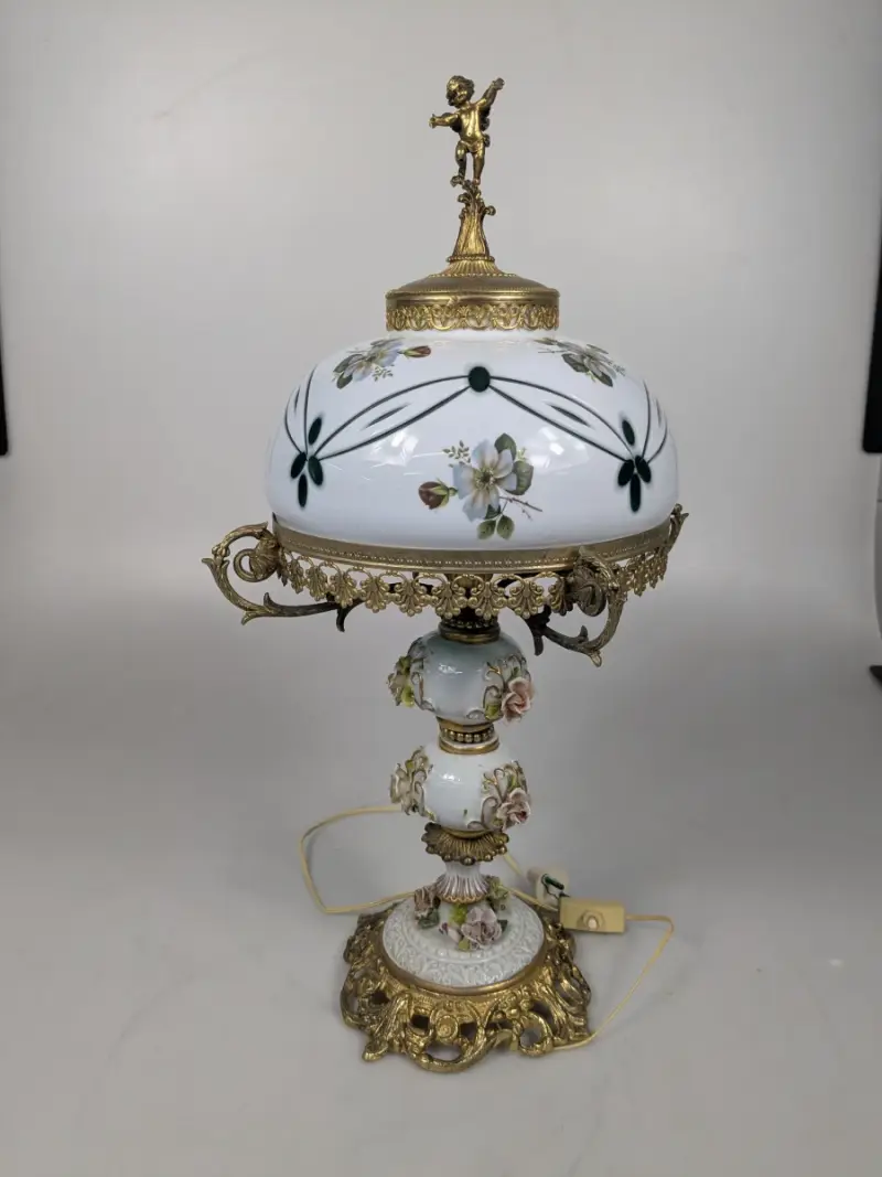 Decoratieve vintage tafellamp met porseleinen kap, bloemenmotief en rijkelijke messingdecoratie – kavel bij De Kringwinkel, Sint-Niklaas
